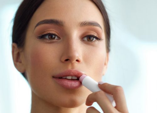 Portrait of a woman applying lip balm | Dermal Fillers | Avail Aesthetics in Cary, Raleigh & Wake Forest, NC
